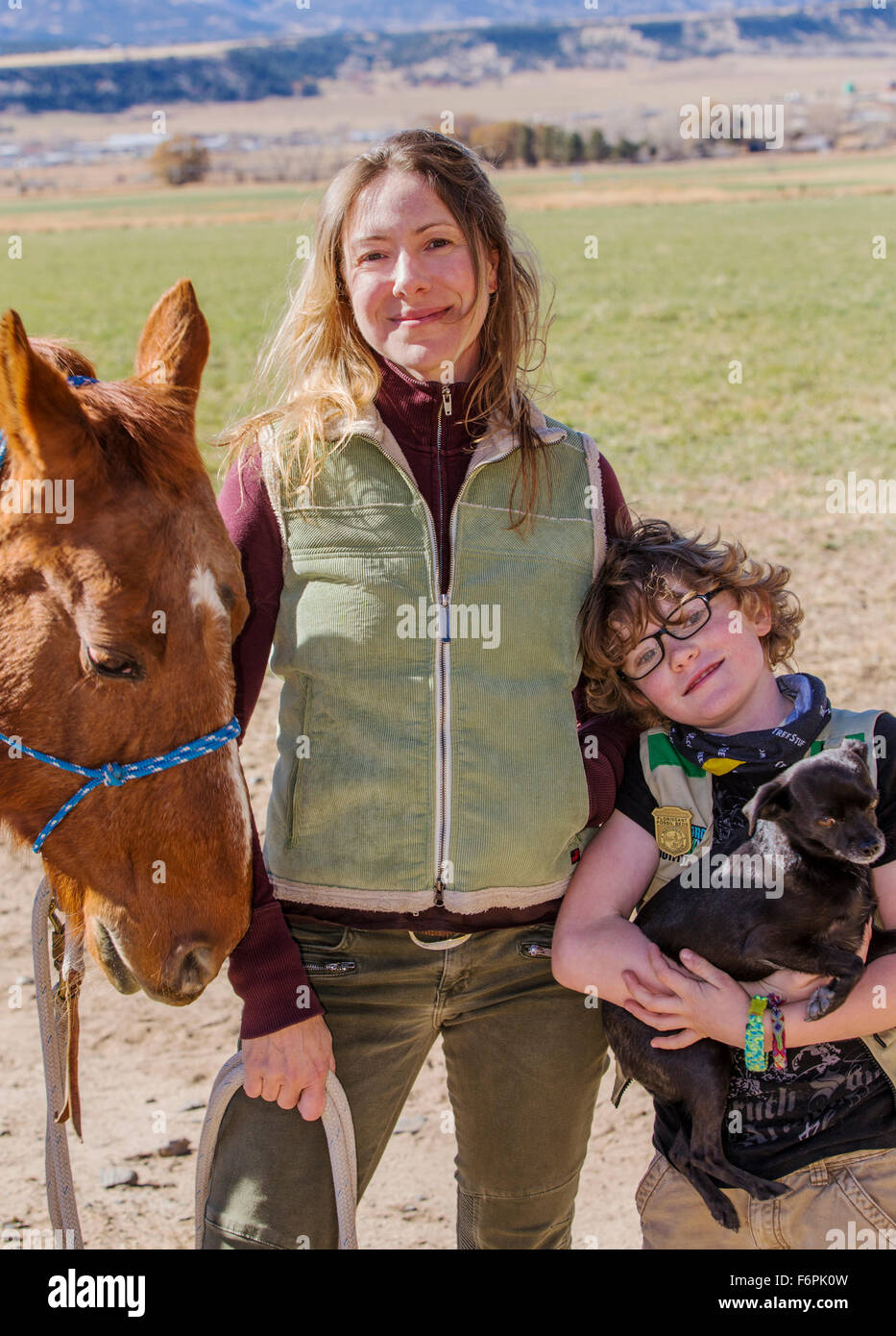 Madre atractiva; joven hijo; caballo y perro mascota plantean fuera de rancho para una fotografía Foto de stock