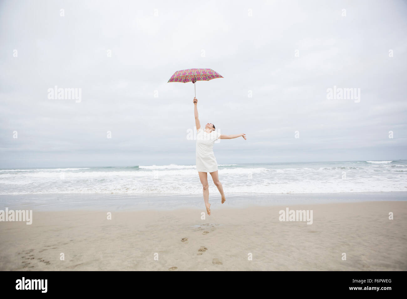 Mujer jugando con sombrilla en la playa Foto de stock
