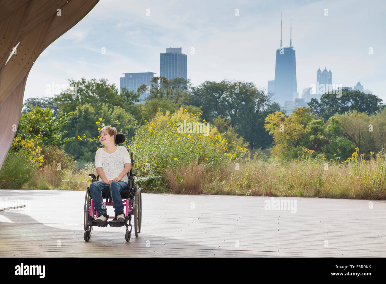 Mujer sentada parapléjico en silla de ruedas bajo el horizonte de la ciudad Foto de stock