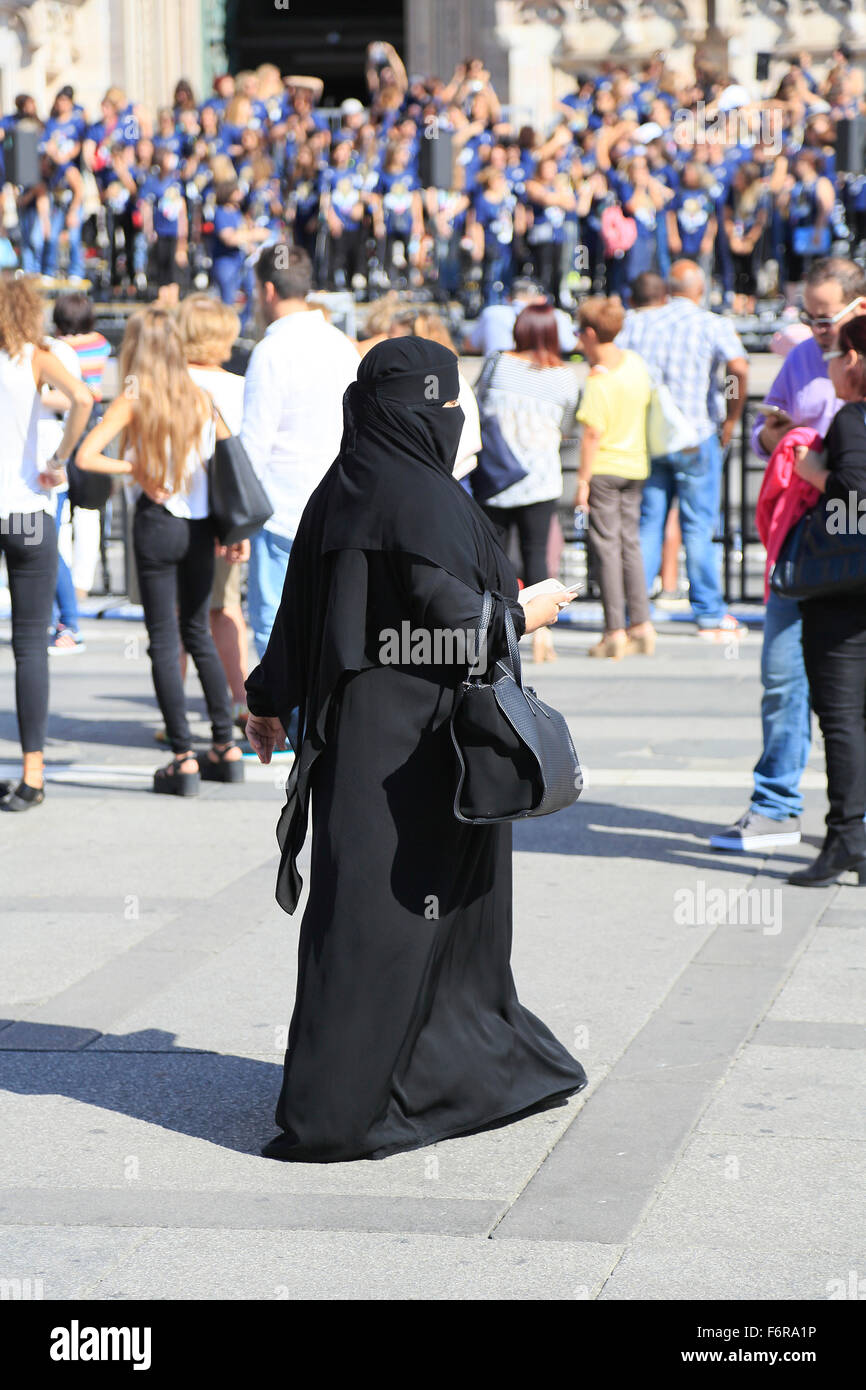Mujer Oriental, vestida con un burka negro, multitud de personas, la Piazza del Duomo de Milán, Lombardía, Italia Foto de stock