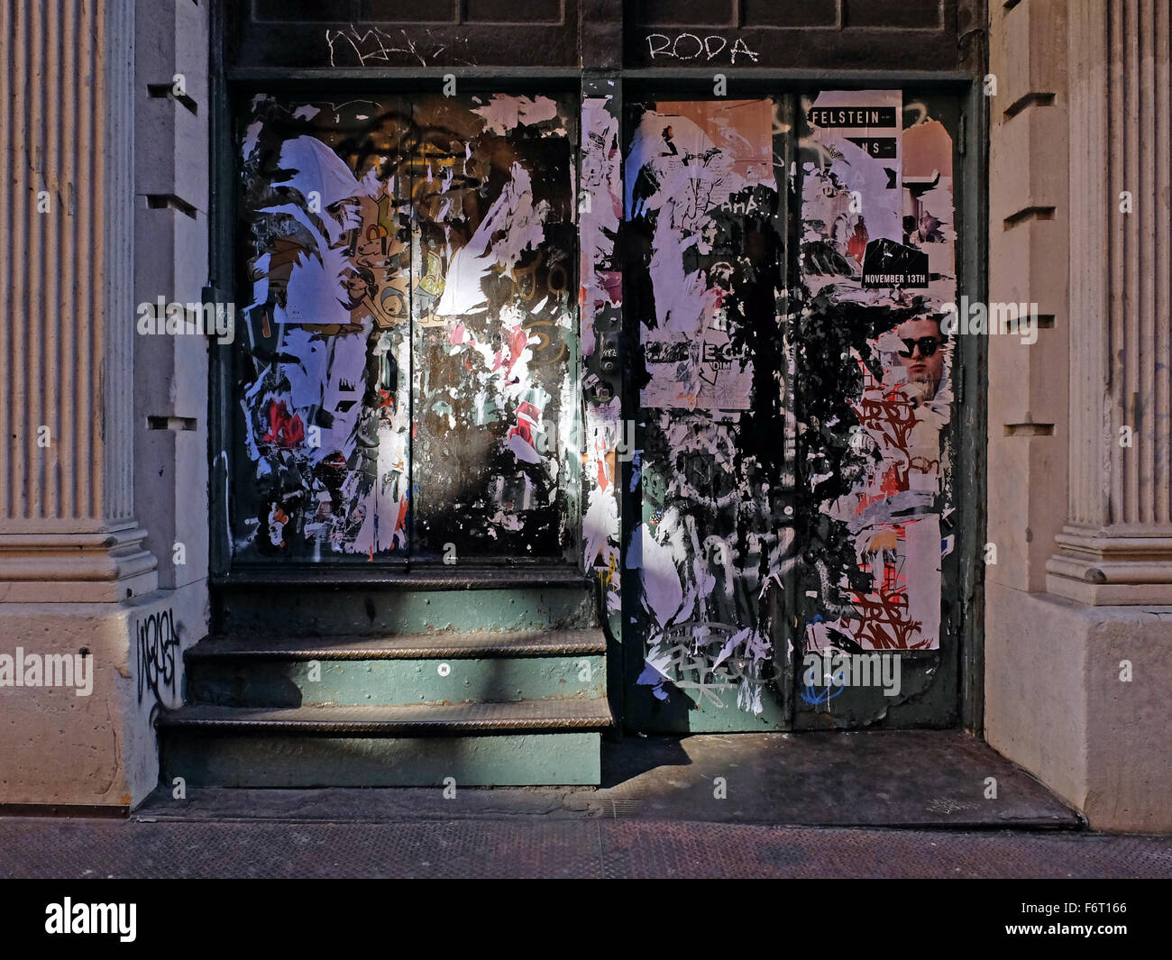 Luz y sombra con patrón desgarrado carteles sobre una puerta en la calle Prince off Broadway en la sección de Soho de Manhattan, Ciudad de Nueva York Foto de stock