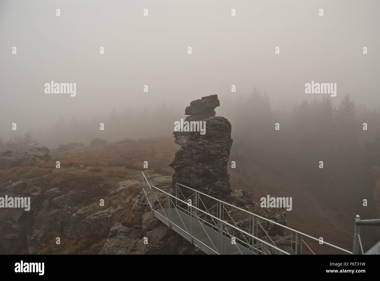 Kamen Vysoky hill de Krusne hory con puente con guardia-rampa y rock durante el brumoso día de otoño Foto de stock