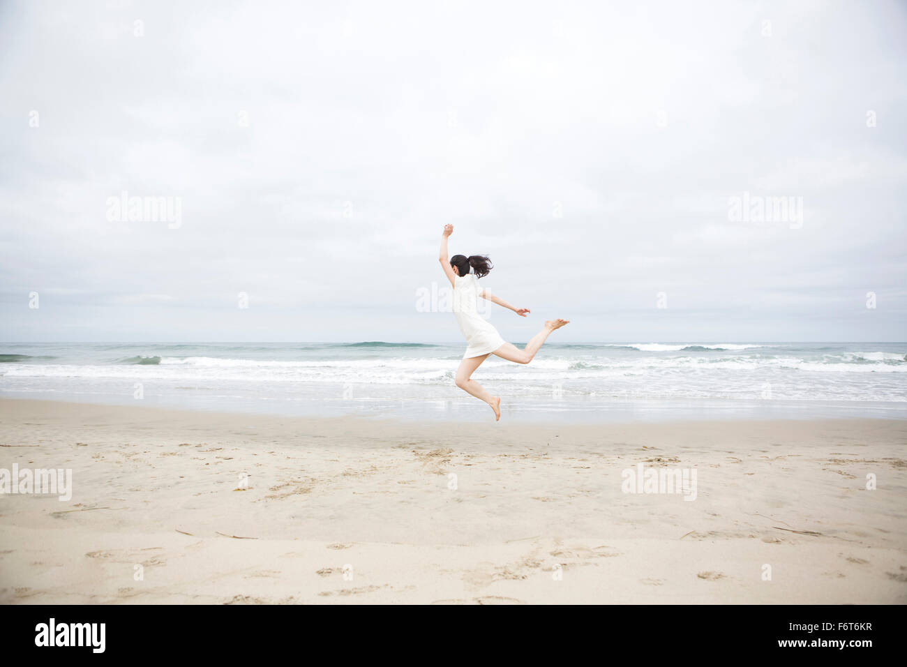Mujer saltando de alegría en la playa Foto de stock