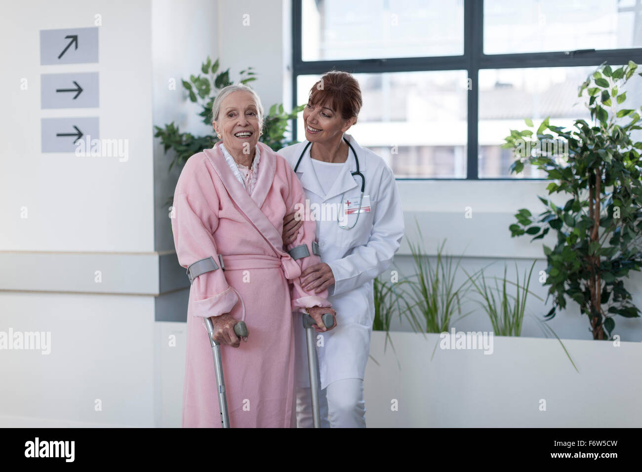 Retrato de una mujer mayor sonriente con muletas en el gimnasio del  hospital