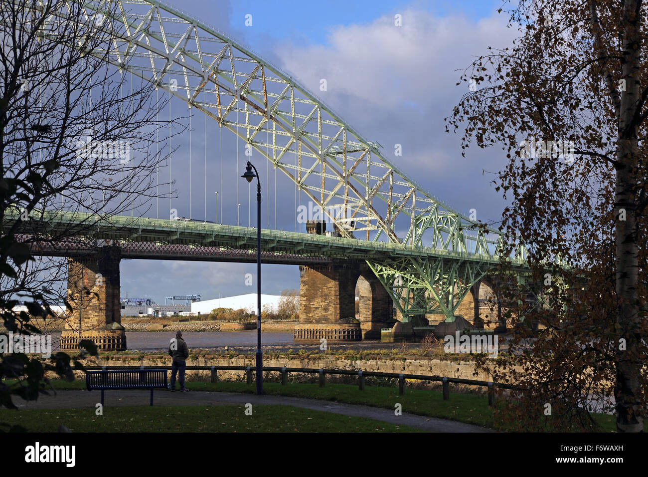 Un hombre mira el Jubileo de Plata de puente que cruza el río Mersey en Runcorn, Cheshire, Reino Unido Foto de stock