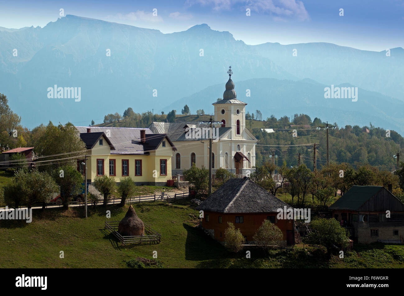 Iglesia en la aldea de Magura, con las montañas de Bucegi, en el fondo, Magura, Transilvania, Rumania Foto de stock
