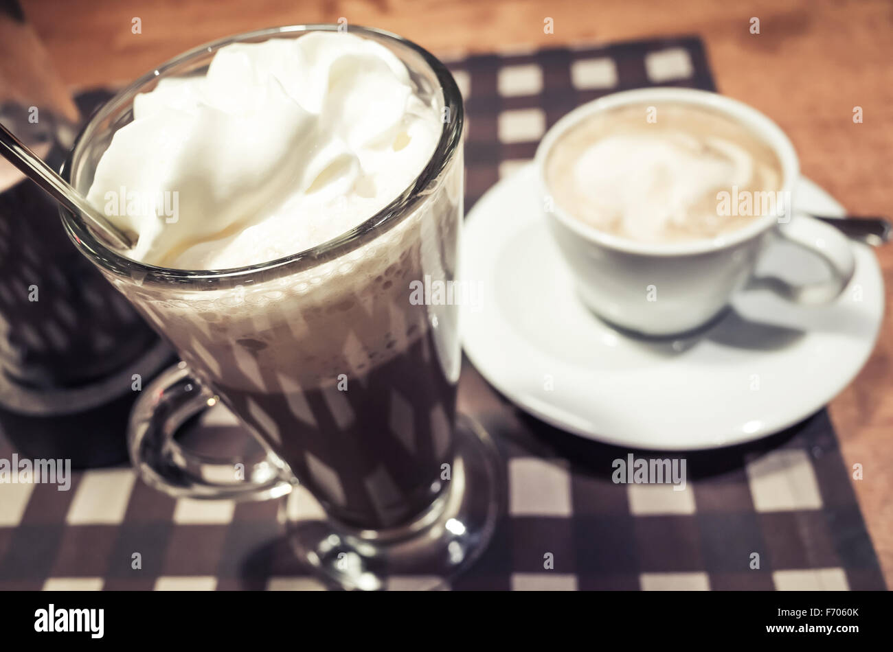 Vaso de chocolate caliente y la taza de café cappuccino de pie en una tabla Foto de stock