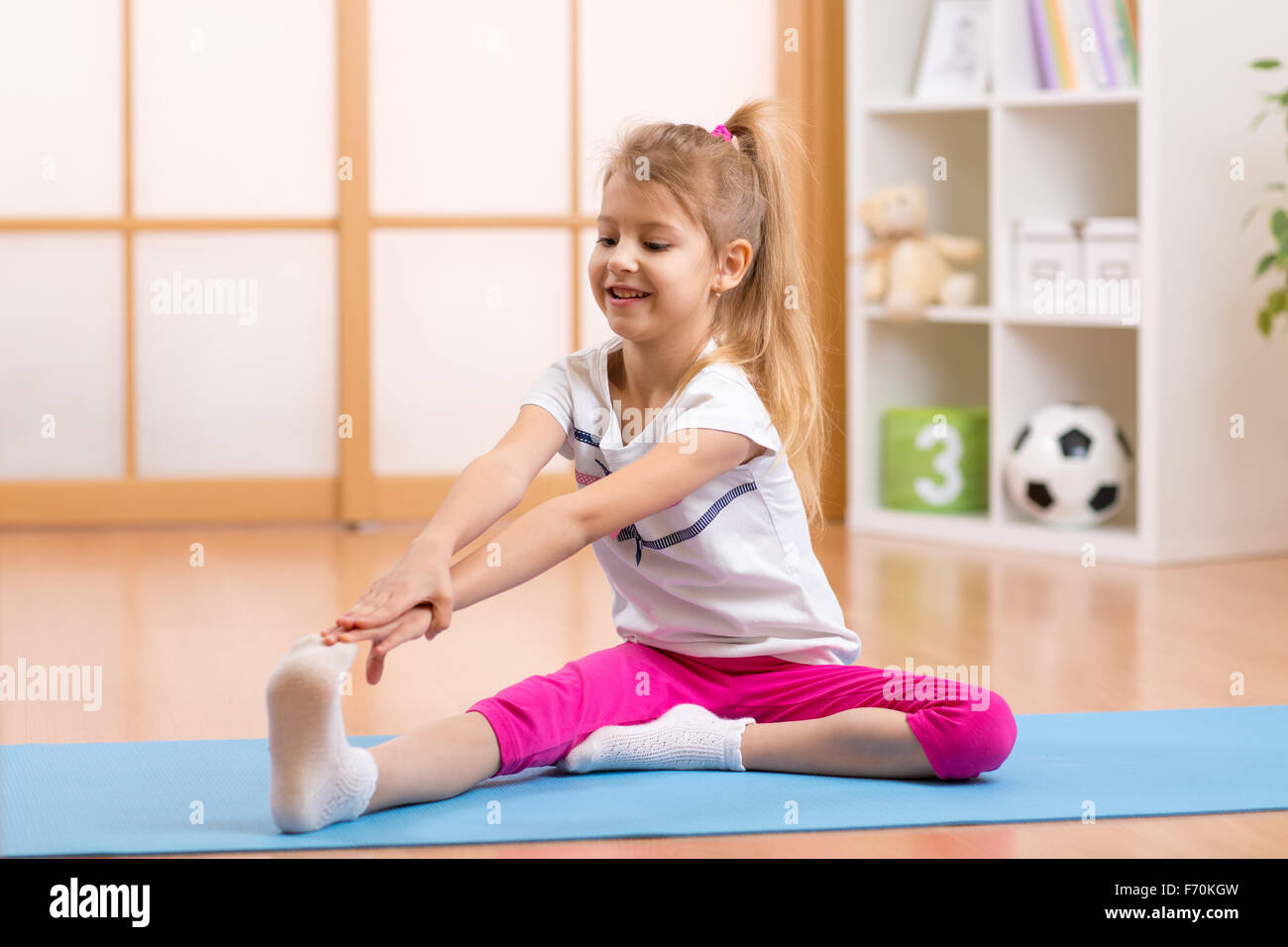 Kid haciendo gimnasia deportiva en casa Foto de stock