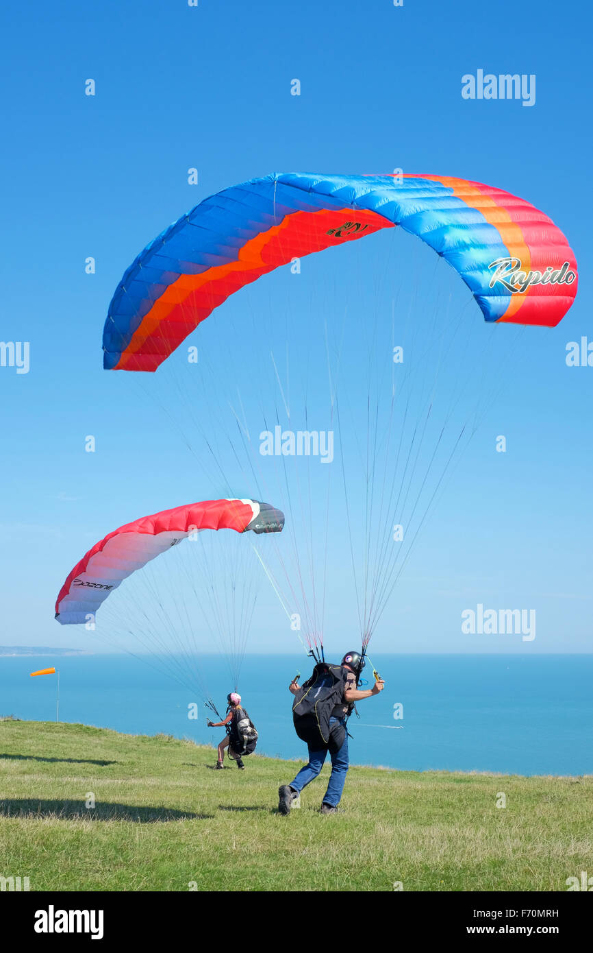 Dos pilotos de parapente prepararse para un despegue en Beachy Head, East Sussex, Reino Unido Foto de stock
