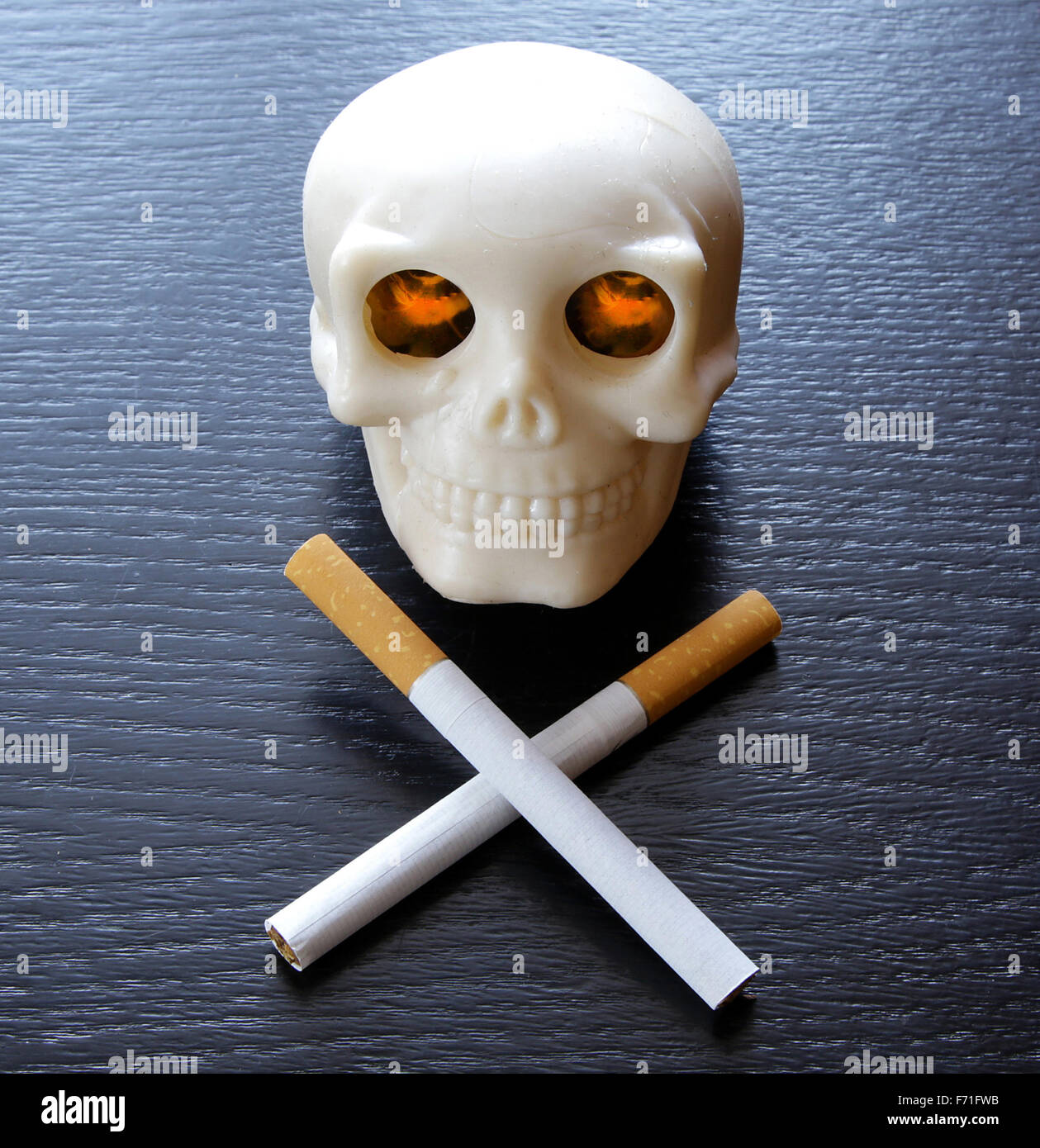 Fumar mata vintage cráneo humano con ardor en los ojos iluminados y  cigarrillos en lugar dos huesos cruzados sobre negro Fotografía de stock -  Alamy