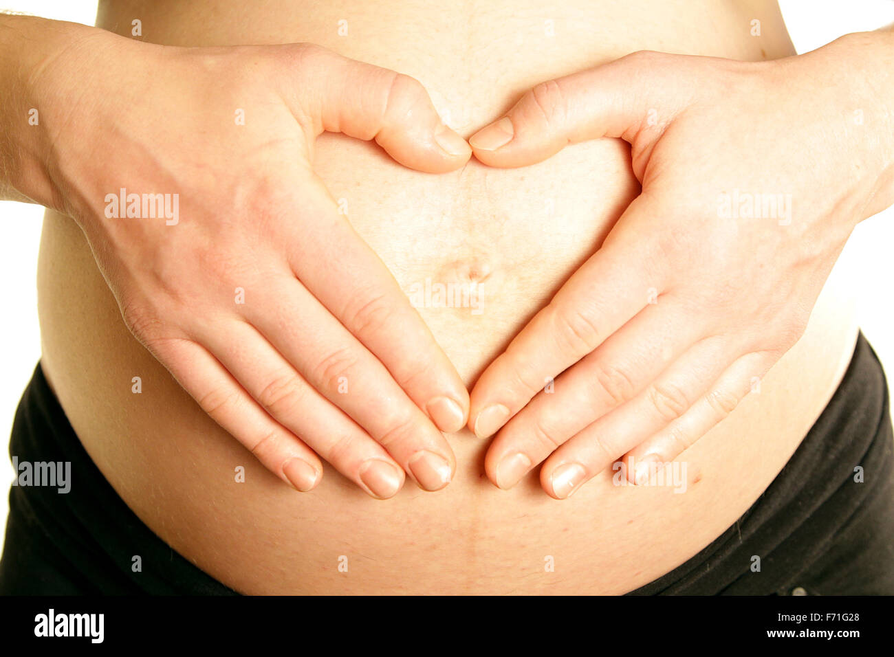 Los brazos de la mamá embarazada vientre barriga forma corazón amoroso bebé fondo blanco. Foto de stock