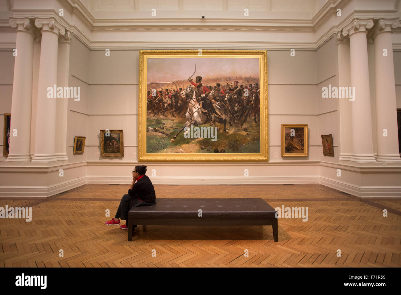 Cansada mujer sentada bench dentro de galería de arte Foto de stock