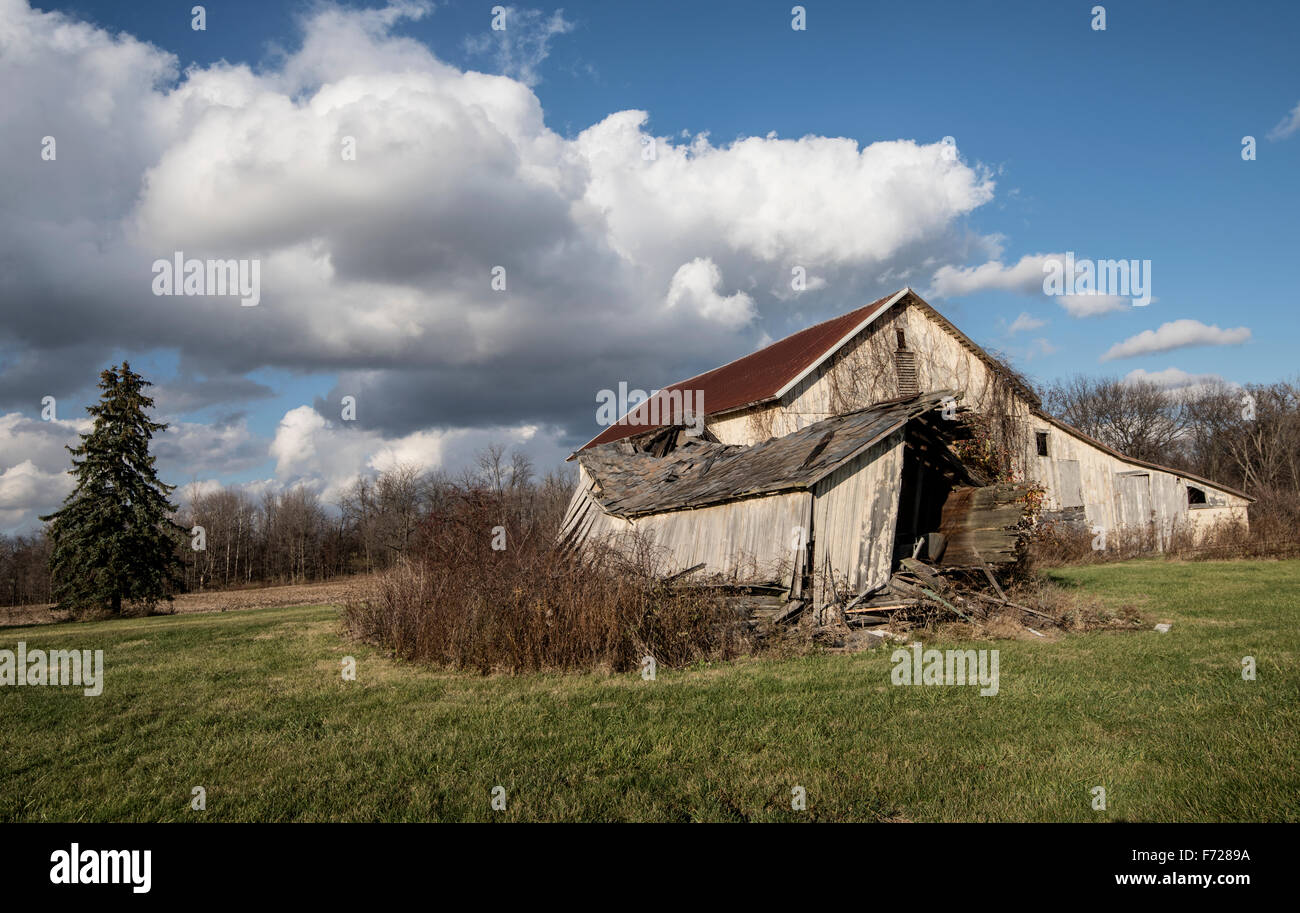 Abandonar el antiguo granero con el cielo azul y las nubes Foto de stock