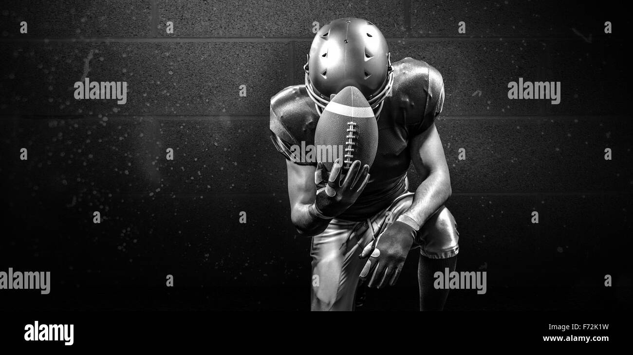 Imagen compuesta de malestar jugador de fútbol americano de rodillas sujetando la bola Foto de stock