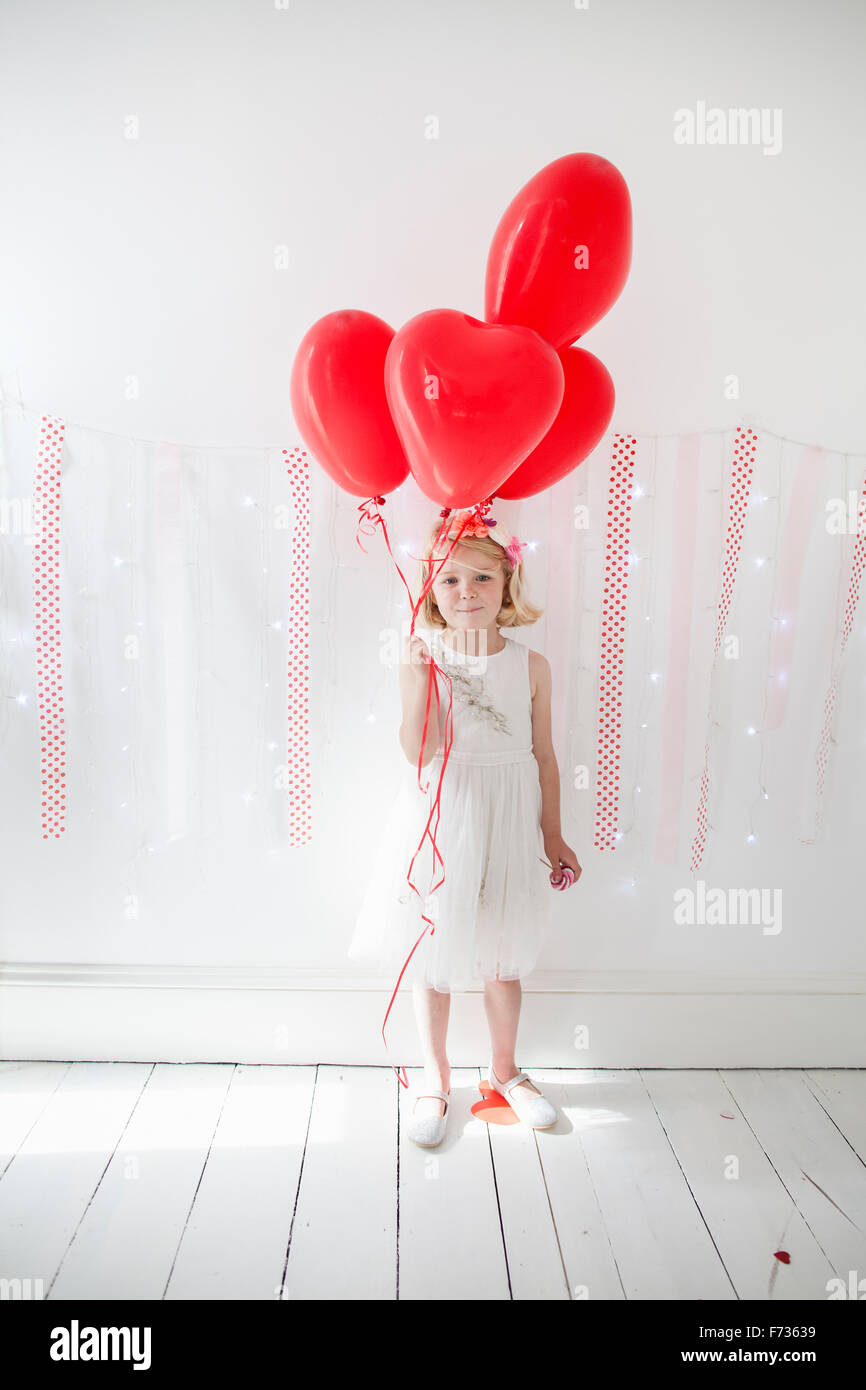 Chica posando para una foto en un estudio del fotógrafo, sosteniendo los globos rojos. Foto de stock