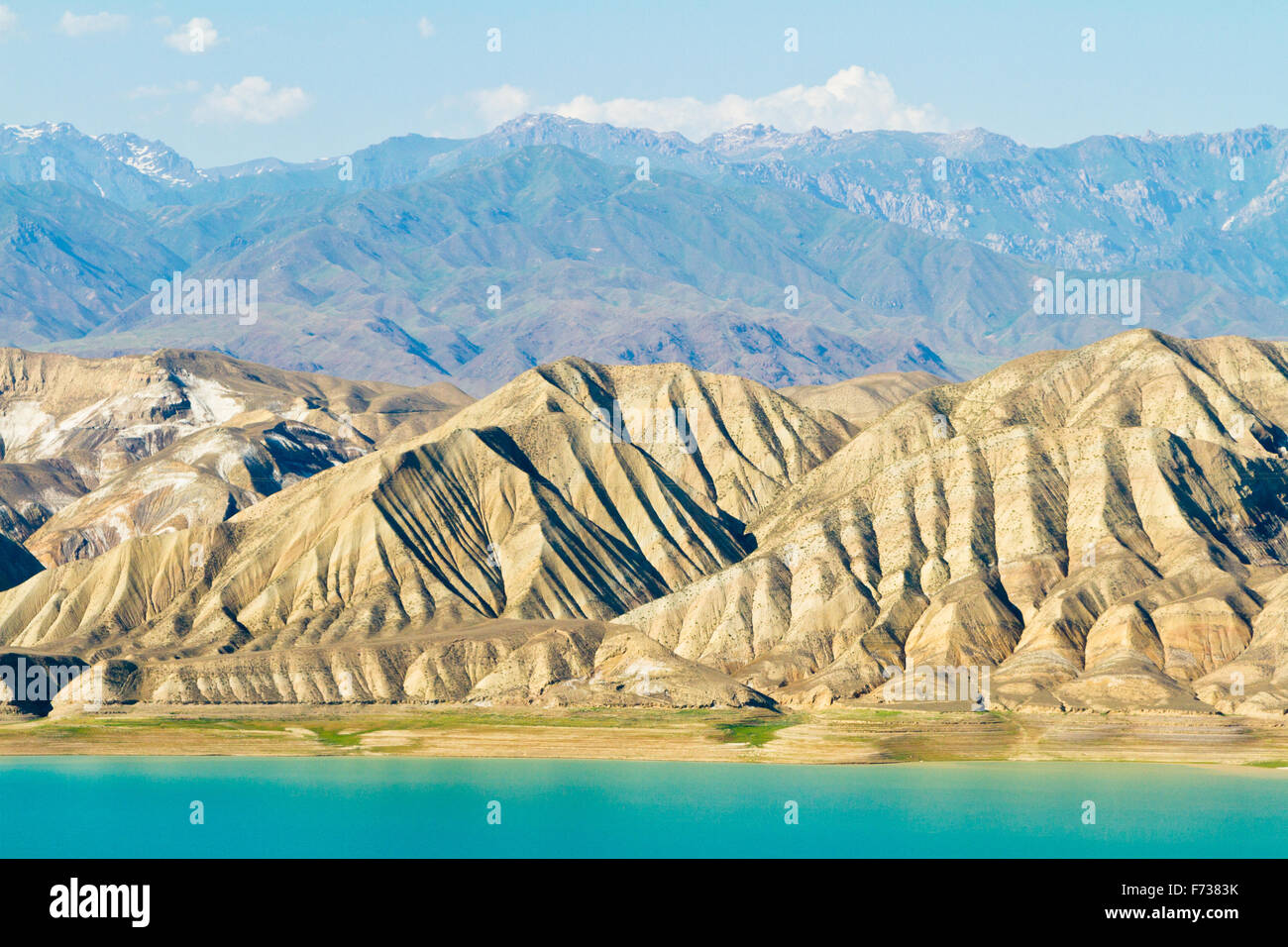 Áridas montañas alrededor del Lago Toktogul y sus cristalinas aguas azules en Kirguistán. Foto de stock