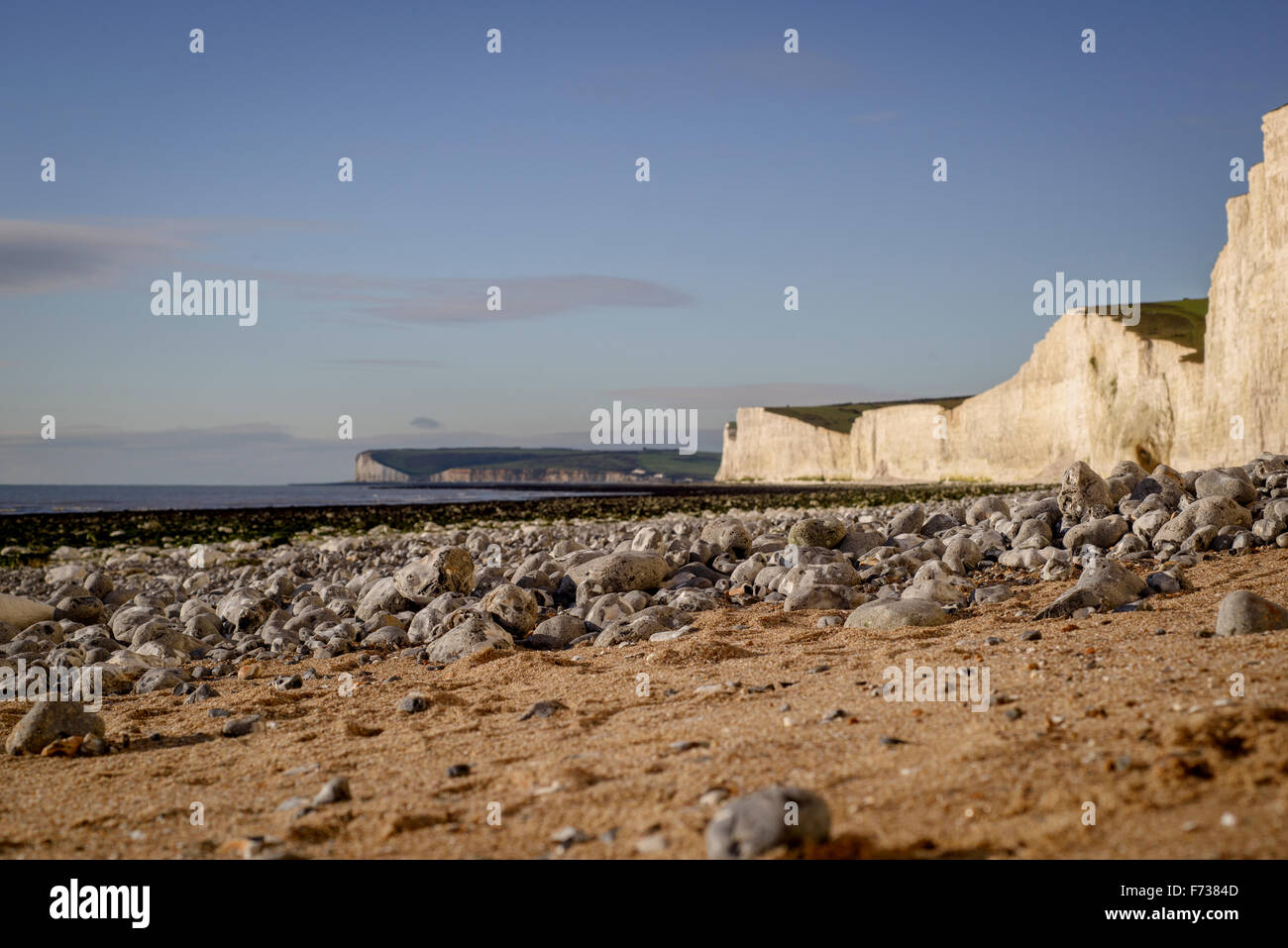 Birling Gap - piedras cerca de la playa en el foco con siete hermanas lejanas costas borrosa en el fondo - East Sussex. Foto de stock