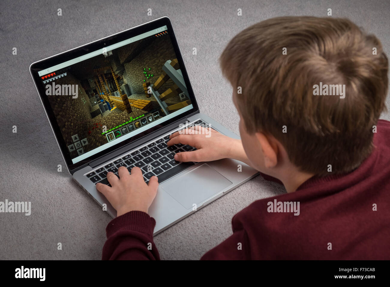 Un niño que está jugando el juego de ordenador Minecraft en un portátil. Foto de stock