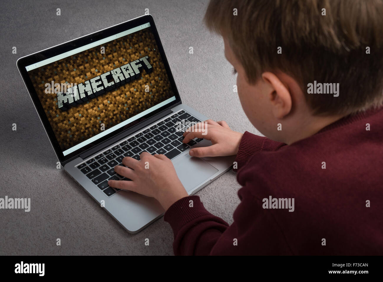 Un niño que está jugando el juego de ordenador Minecraft en un portátil. Foto de stock