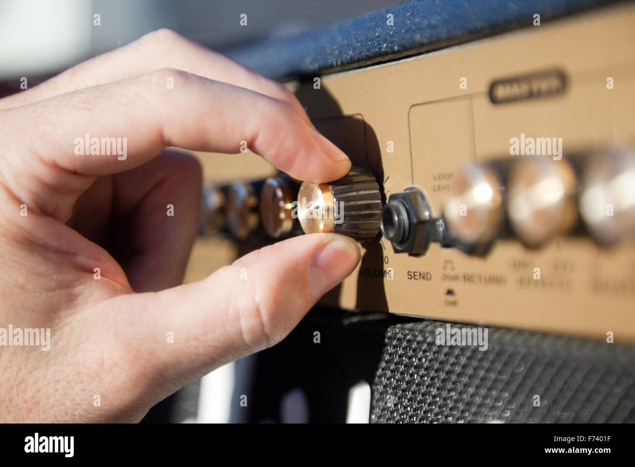 Cerca de una mano controlando el volumen de un amplificador. Foto de stock