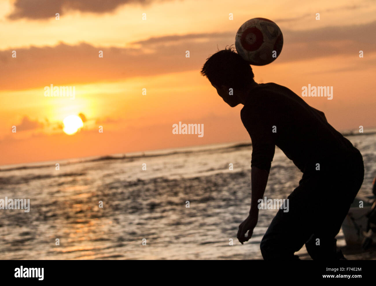 Jugador de fútbol encabeza una pelota en la playa al anochecer, Zihuatanejo, Guerrero, México. Foto de stock