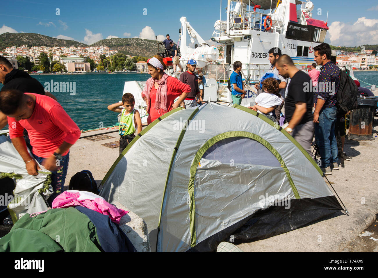 Migrantes sirios que huían de la guerra y escapar a Europa, que han desembarcado en la isla griega de Lesbos, en la costa norte a Efthalou, aquí con un barco de la patrulla fronteriza en el fondo. Hasta 4.000 migrantes un día se desembarque en la isla y aplastante de las autoridades. Son traficked ilegal turca por traficantes de personas que cobran hasta $2,000 por persona para un viaje de media hora en un superpoblado inflateable barco desde la península turca a Lesvos. Foto de stock