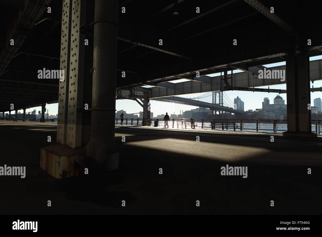Un hombre corre, otro hombre camina a lo largo del East River Esplanade viaducto, Nueva York Foto de stock