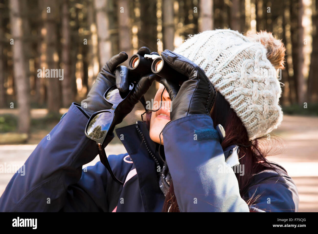 Mujer joven de 25 a 30 años de edad- mirando a través de un par de binoculares Foto de stock