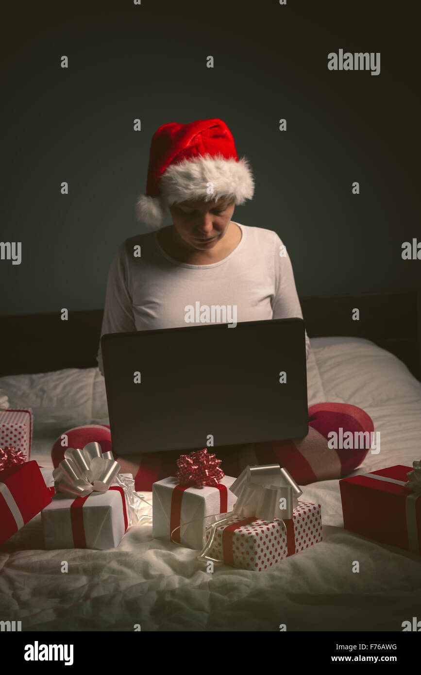 Mujer Solitaria navegando por internet en la víspera de Navidad, la hembra adulta utilizando equipo portátil para acceder a sitios de redes sociales, tonos retro Foto de stock