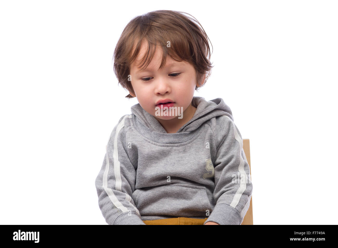Un lindo hijo de 3 años con una expresión triste sobre un fondo blanco. Foto de stock