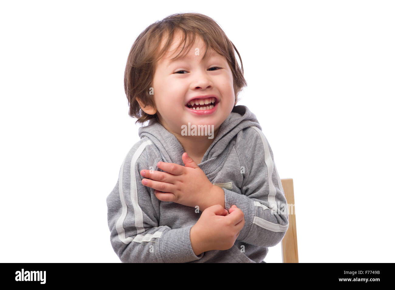 Un lindo hijo de 3 años con una feliz expresión temblando y fingir estar frío sobre un fondo blanco. Foto de stock