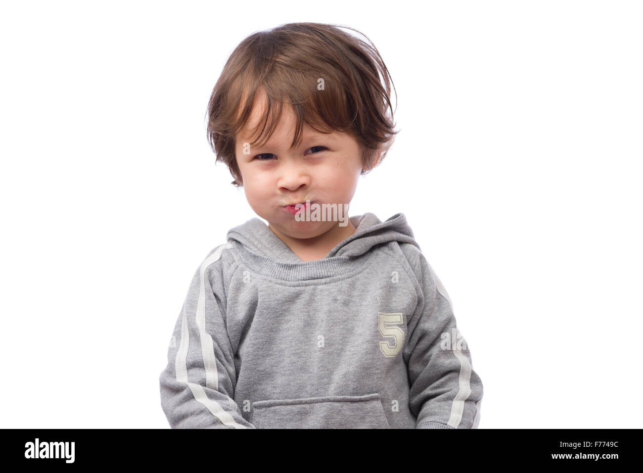 Un lindo hijo de 3 años con una airada expresión sobre un fondo blanco. Foto de stock
