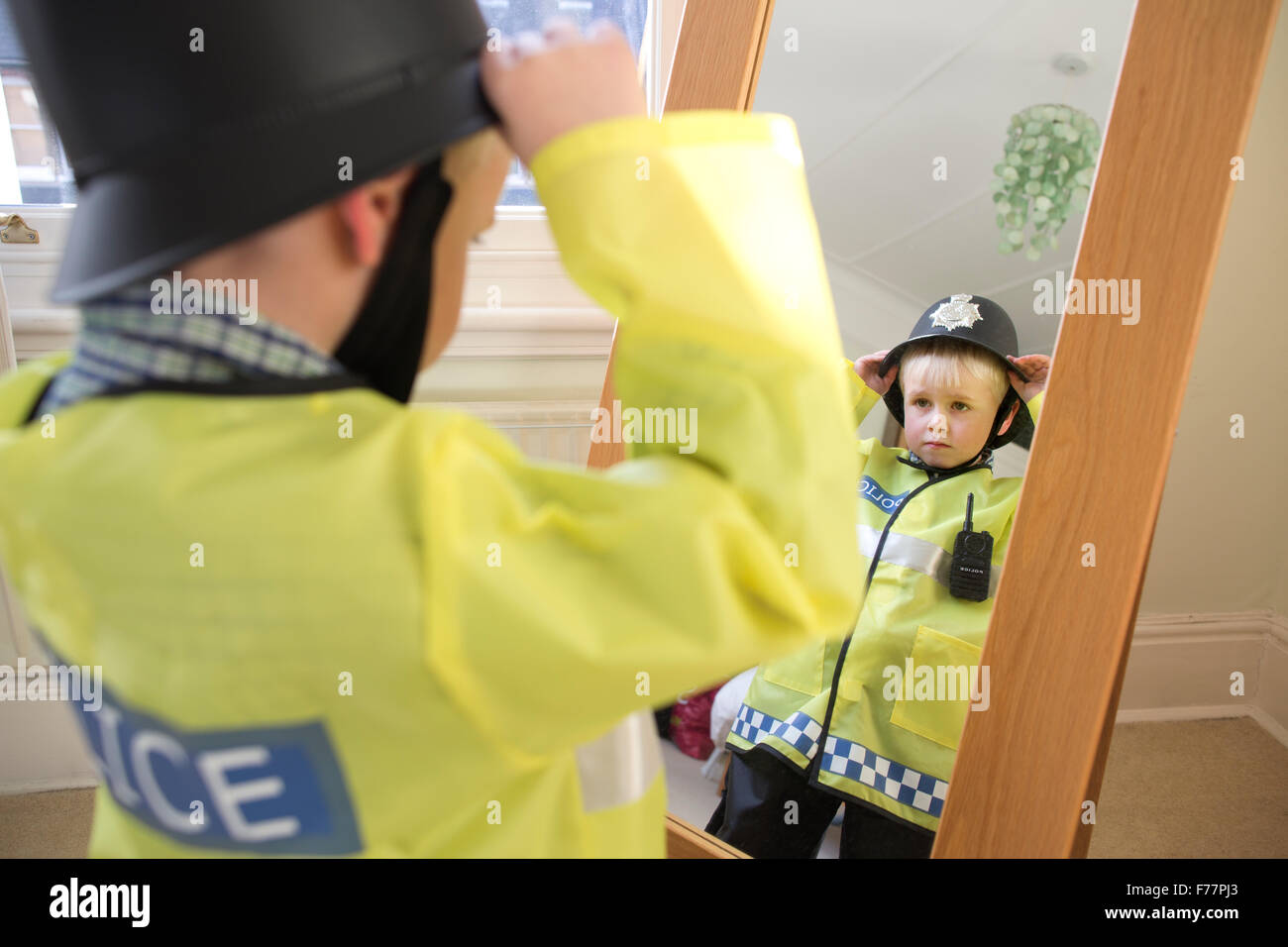 Niño (edad 4) vistiendo su British "Bobby" oficial de policía disfraz  delante del espejo en casa en su casa adosada de Londres, Reino Unido  Fotografía de stock - Alamy