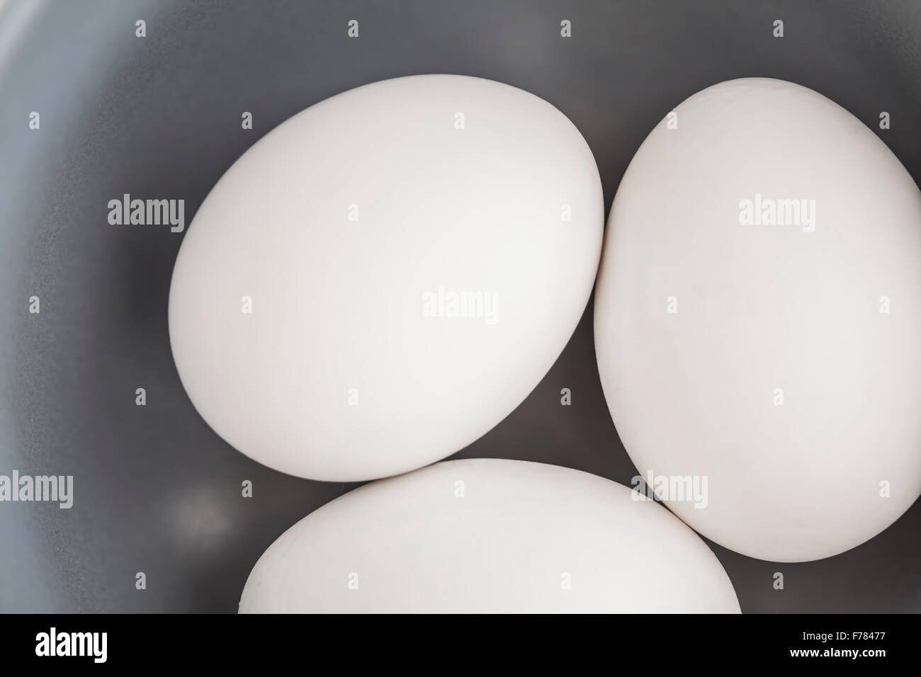 Tres huevos blancos de cerca en un tazón Foto de stock