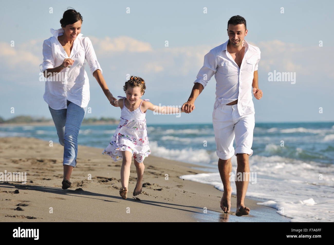 Feliz familia joven en ropa blanca divertirse en vacaciones en Playa  Hermosa Fotografía de stock - Alamy
