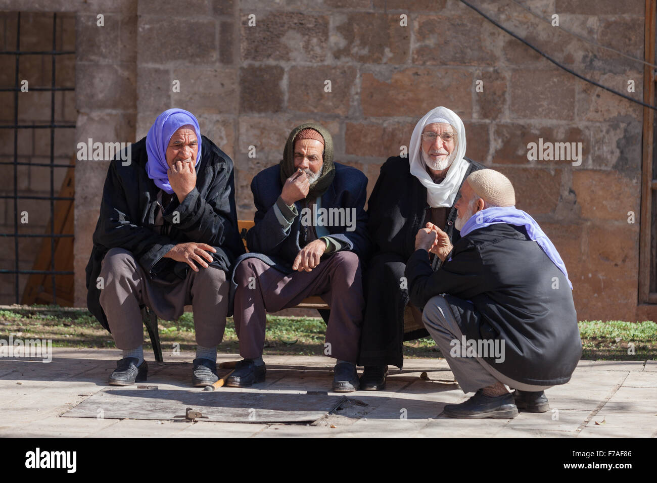Los viejos hombres vestirse con su tradicional se sitúa delante de las areniscas de un antiguo edificio en la llanura de Harran, Sanliurfa, Turquía Foto de stock