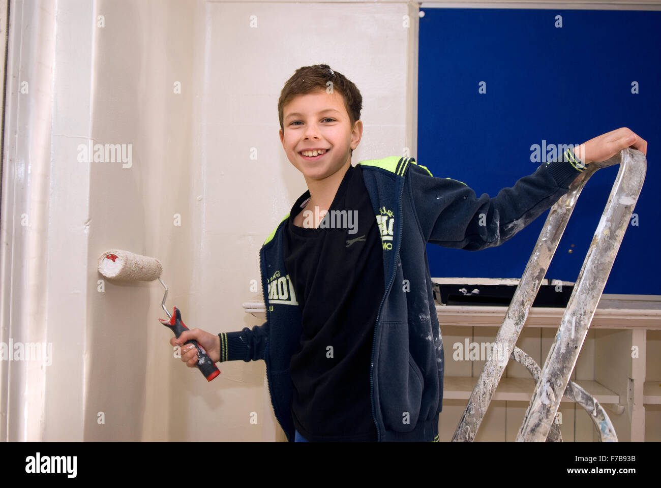 Uno de 10 años Cub con rodillo de pintura ayudando con la remodelación de la nueva casa para un grupo de Scouts locales, Bordon, Hampshire... Foto de stock