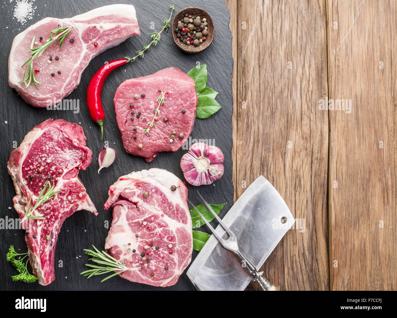 Filetes de carne cruda con especias sobre la placa de corte de madera. Foto de stock