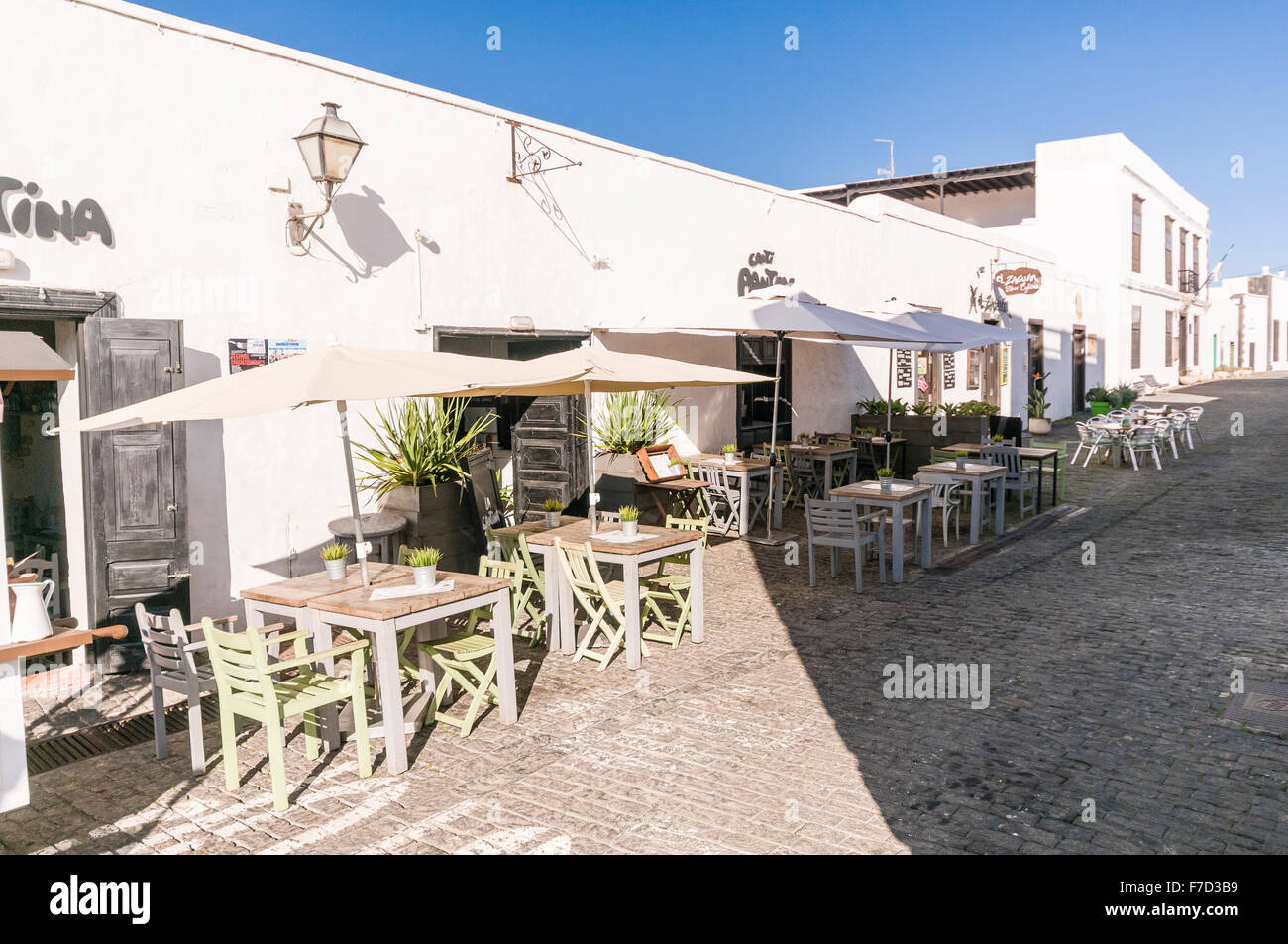 Tablas vacías fuera de cafés en una localidad española Foto de stock