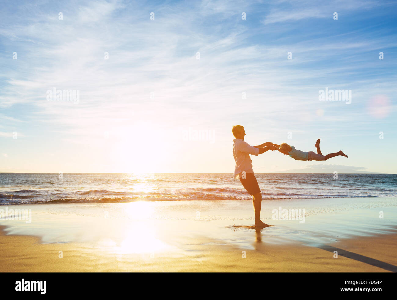 Feliz alegre, padre e hijo, tocando en la playa al atardecer. Concepto de familia paternidad Foto de stock