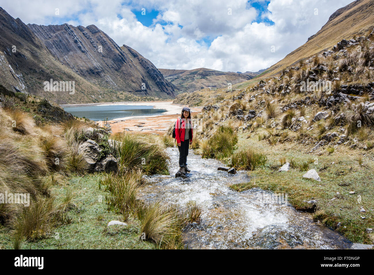 Mujer trekking y cruzar arroyo en el lago Quengococha en las montañas cerca de Cajabamba en Perú Foto de stock