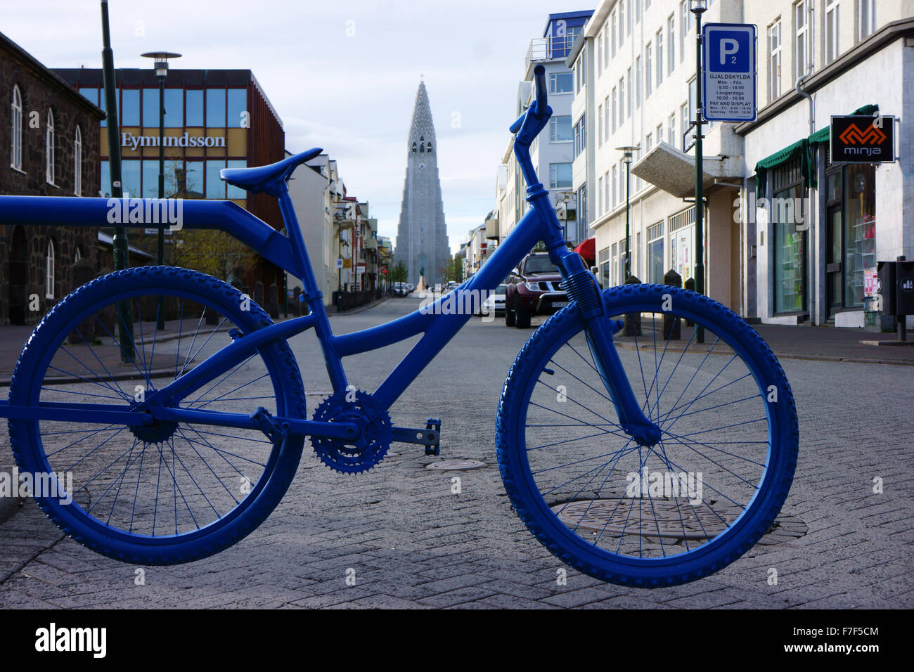 Bicicleta azul marca la zona peatonal, en el centro de la ciudad, en la parte posterior de la catedral moderna Rejkiavik Hallgrimskirkja, Islandia Foto de stock
