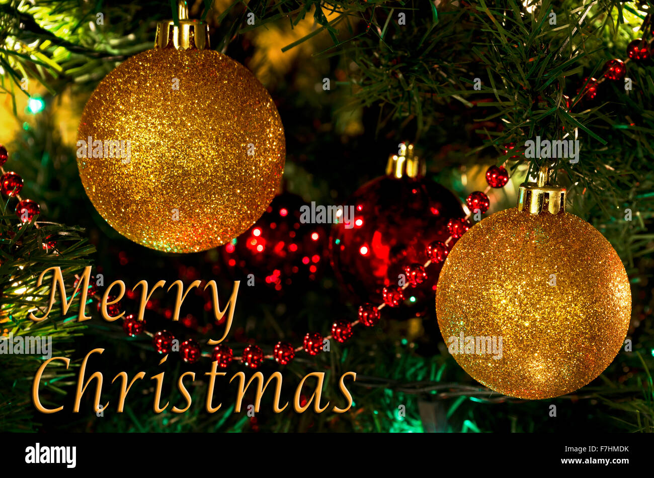 Balón de Oro brillantes ornamentos en un árbol de Navidad con un saludo de Feliz Navidad. Foto de stock