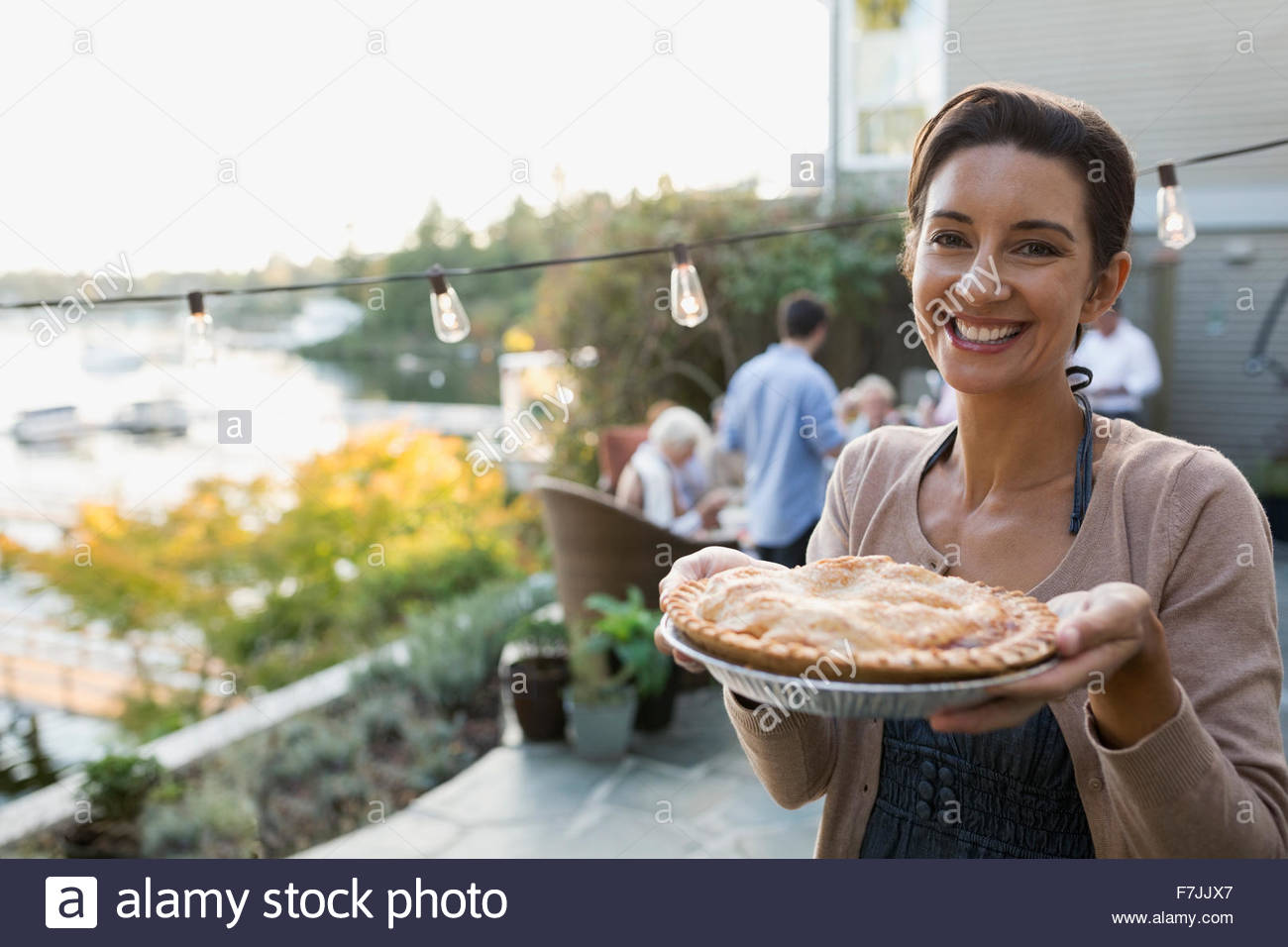 Retrato mujer sonriente servir tarta casera lakeside patio Foto de stock