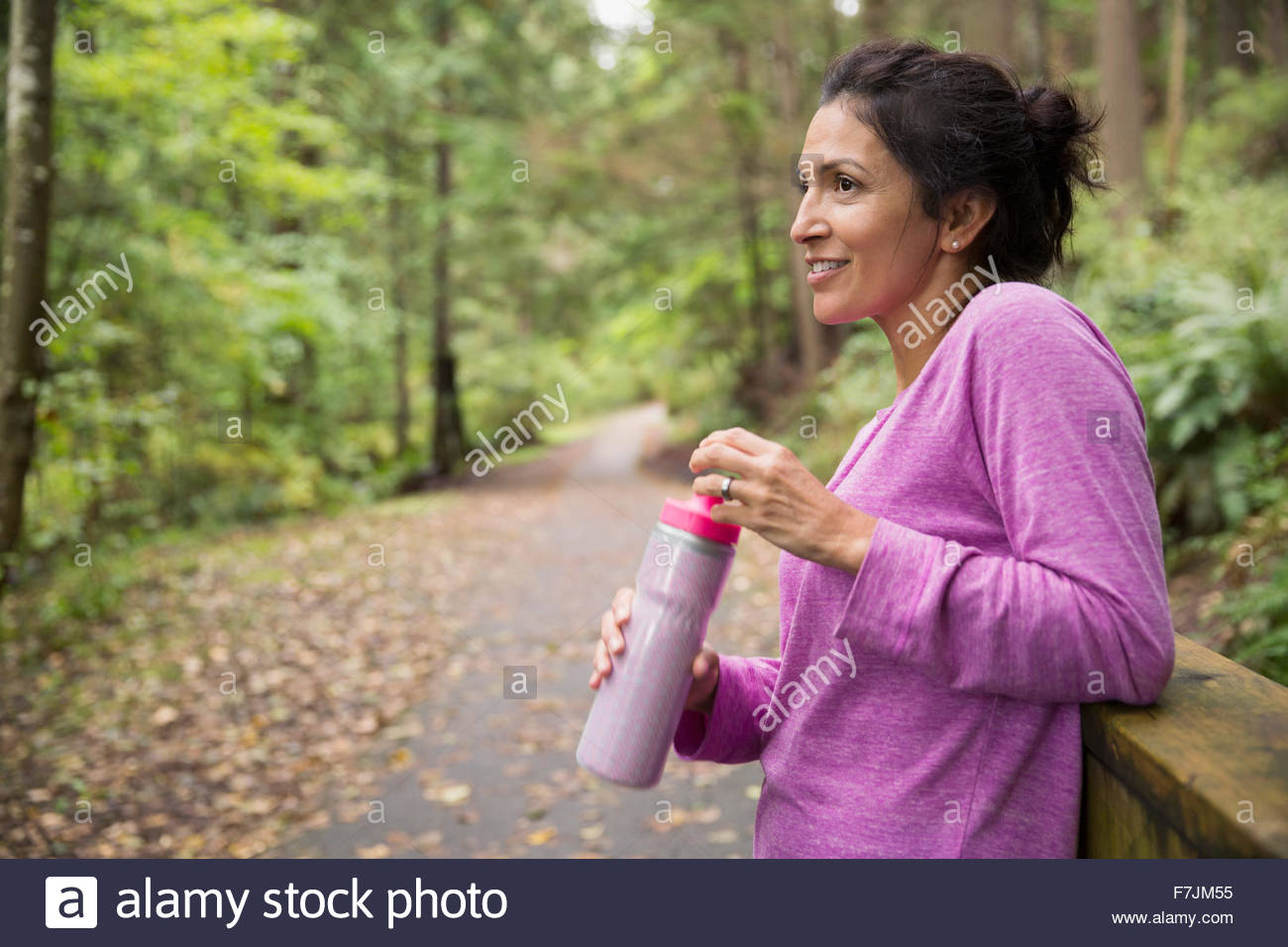 Mujer sonriente tomando un descanso agua potable woods Foto de stock
