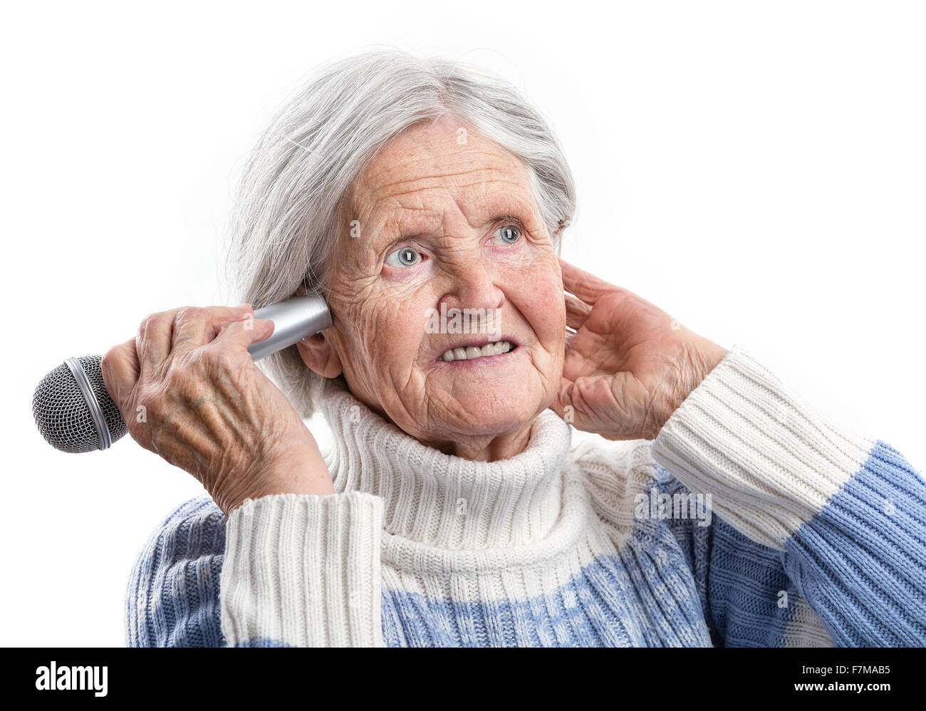 Anciana sosteniendo el micrófono cerca de una oreja. Los problemas de audición. Foto de stock