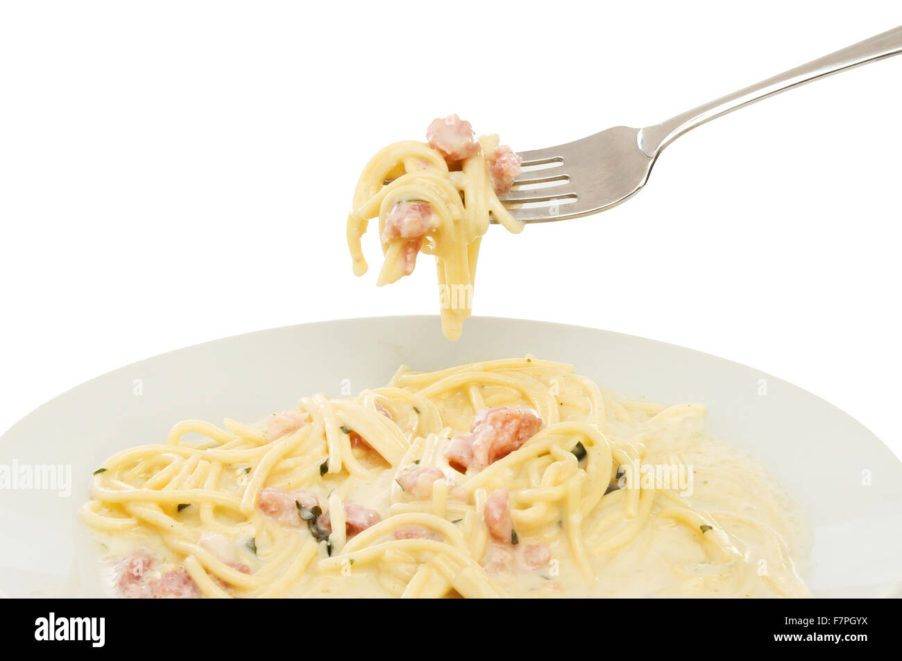 Espaguetis Carbonara en un cuenco y en una horquilla contra un fondo blanco. Foto de stock