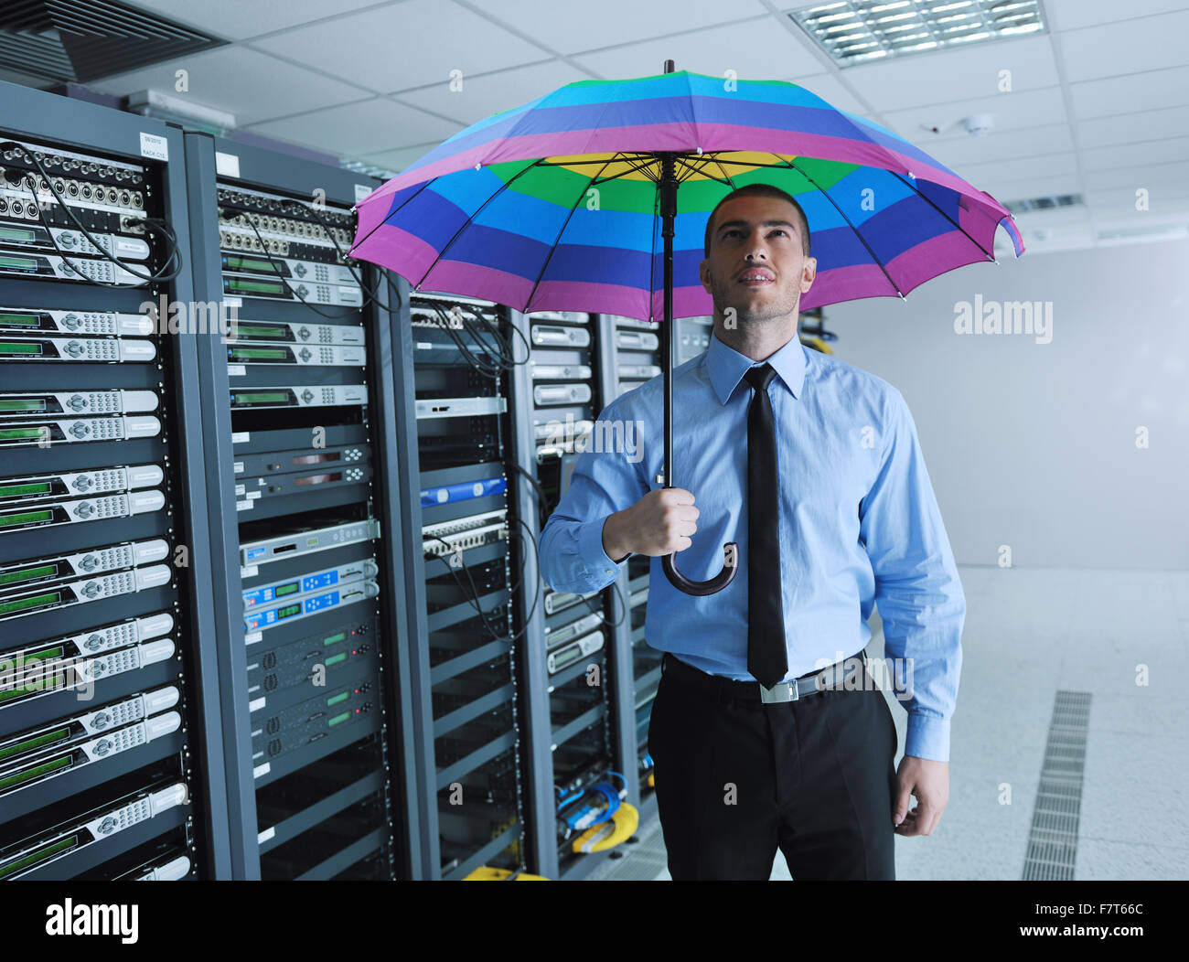 Joven apuesto hombre de negocios ingeniero en empresario mantenga arco iris  de colores paraguas en server datacenter habitación y que representa la  seguridad y el concepto de protección de software antivirus Fotografía