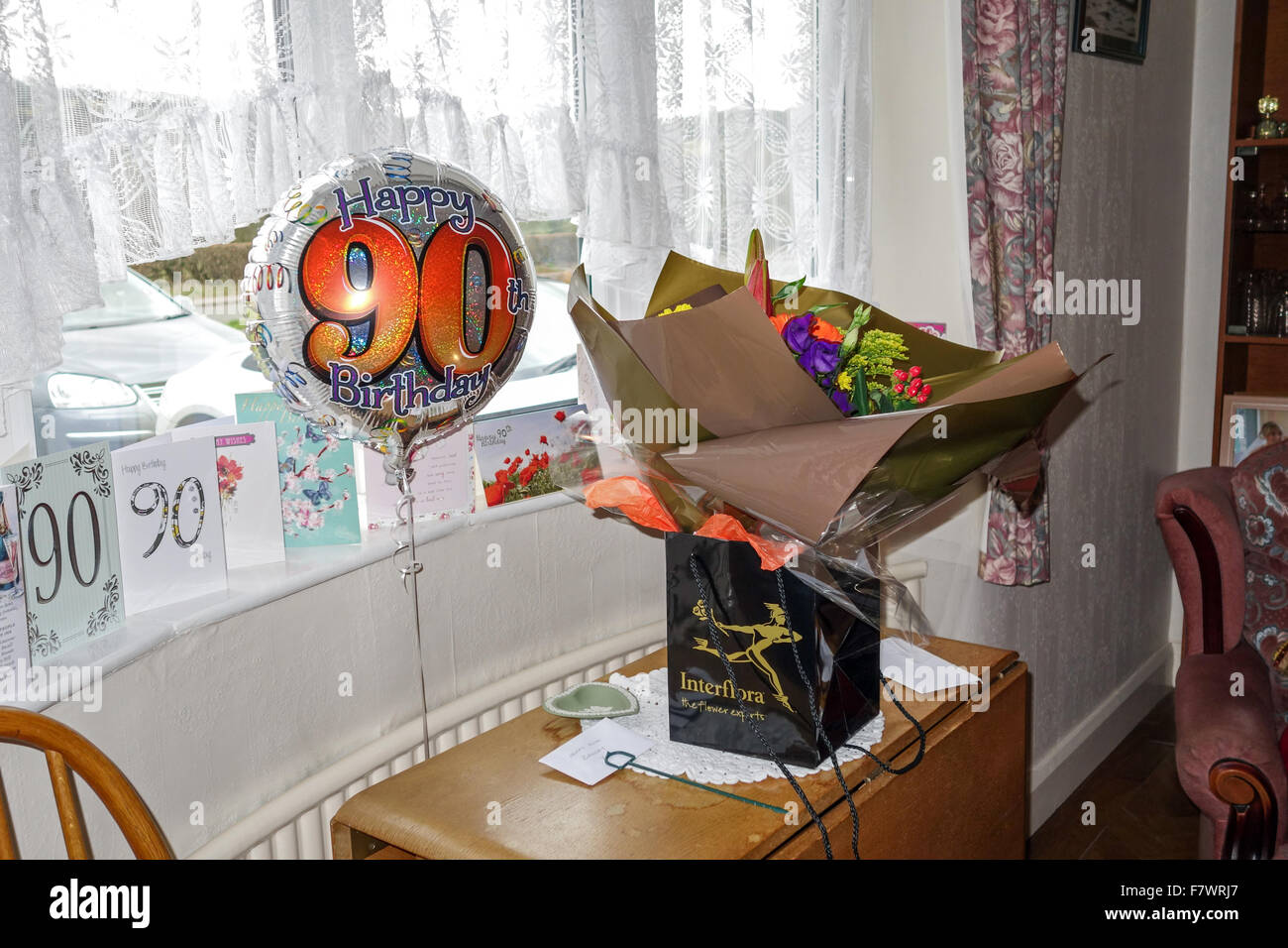 Globo con 90 Feliz cumpleaños, tarjetas y un ramo de flores Foto de stock