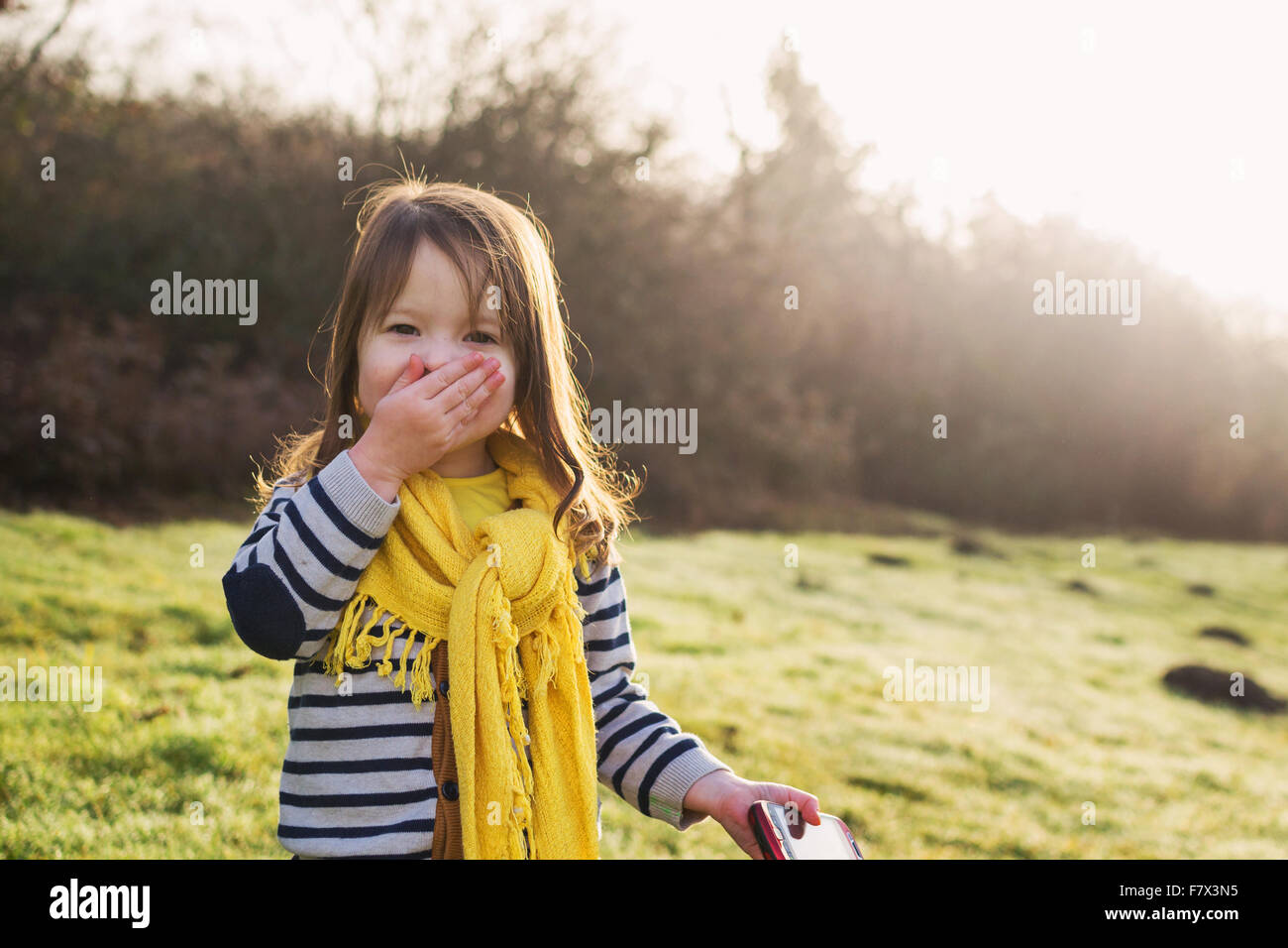 Laughing chica con mano delante de la boca, sujetando el teléfono móvil Foto de stock